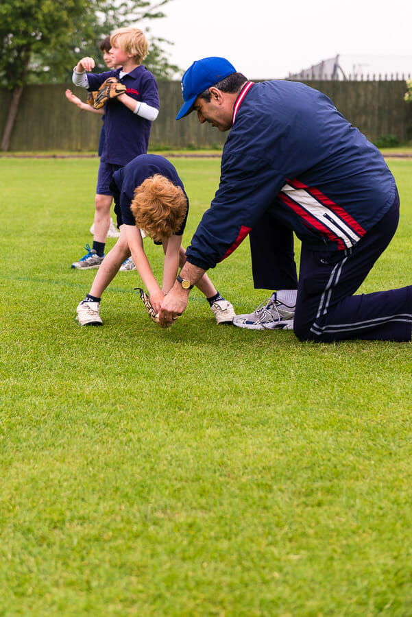 Youth coach teaching little leaguer how to field